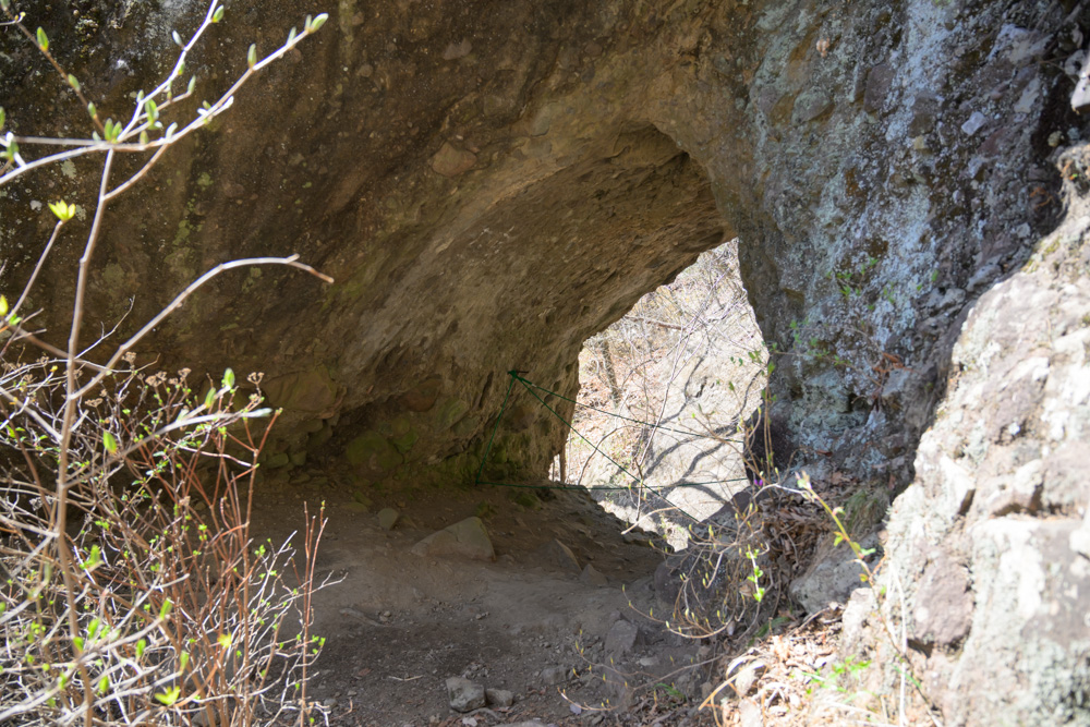 第三石門の岩場に設置された鎖を使って登る登山者。大きな岩壁に囲まれた迫力ある場所で、妙義山らしい険しい地形とスリルを感じられるスポット。