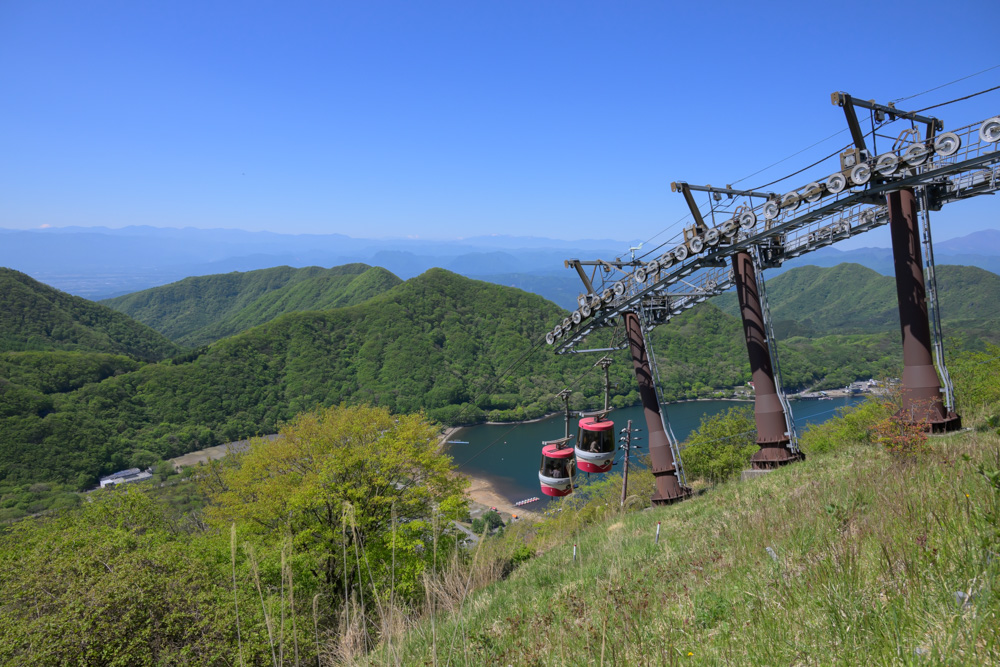 榛名富士山頂付近から見た榛名湖の景色。青く広がる榛名湖とロープウェイが見え、新緑に囲まれた爽やかな風景が広がっている。