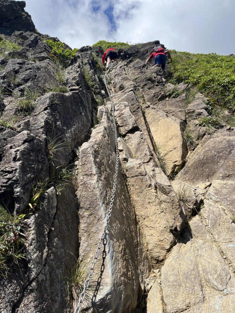 西黒尾根の鎖場を登る登山者たち。切り立った岩の間に鎖が設置されている
