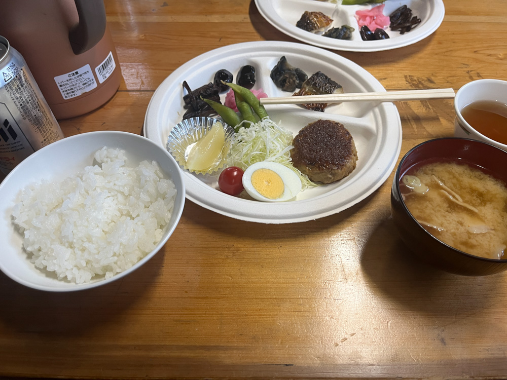 肩の小屋の晩ごはん。ご飯、味噌汁、ハンバーグ、煮物などが並んでいる