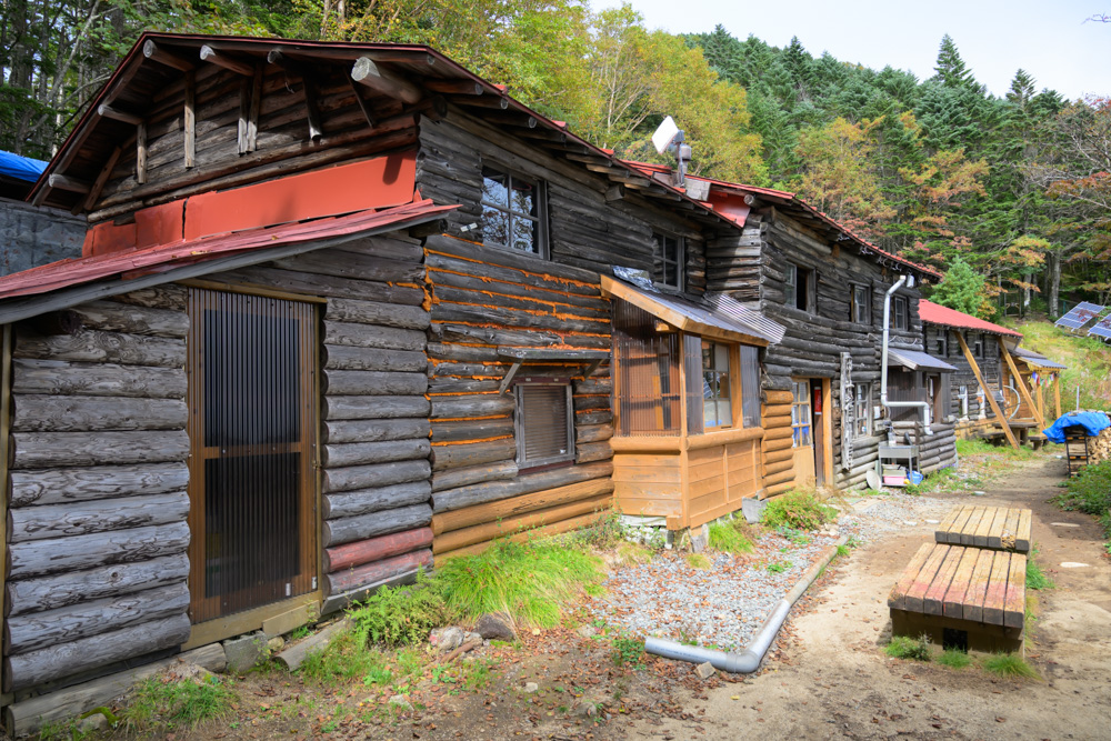 丸太を積んだ壁の甲武信小屋と、前に置かれた木のベンチ