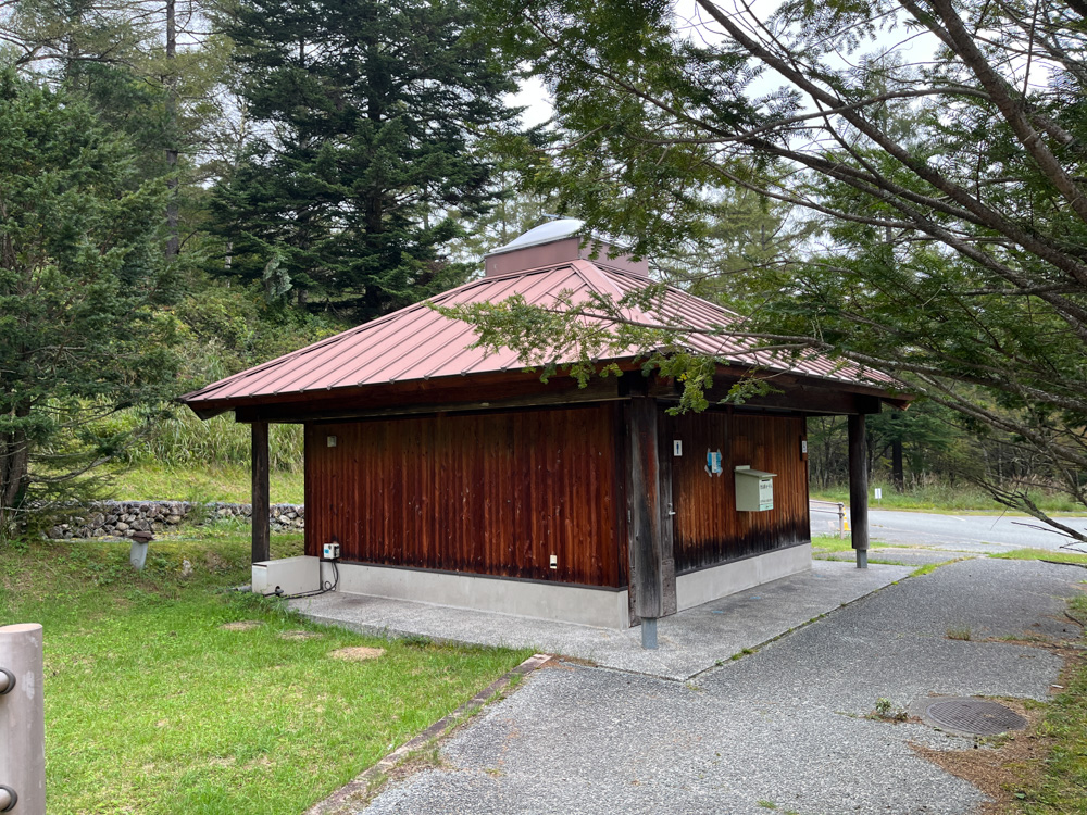 赤い屋根の木造トイレと舗装された通路