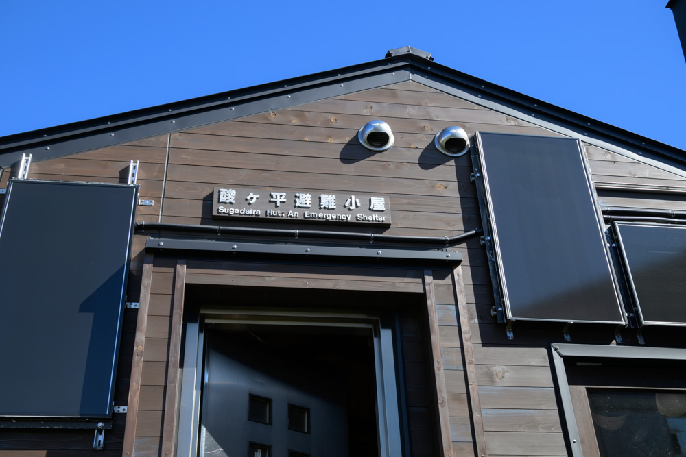 酸ヶ平避難小屋の入口。壁に「酸ヶ平避難小屋」の看板がかかっている