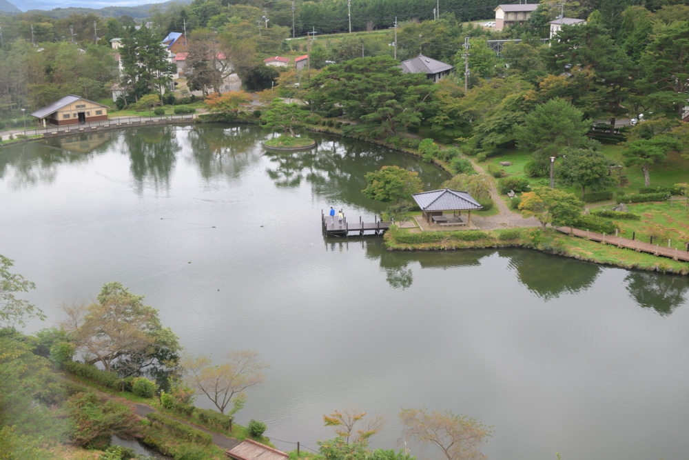 高い位置から見下ろした池。岸に東屋と桟橋があり、周りを木々が囲んでいる