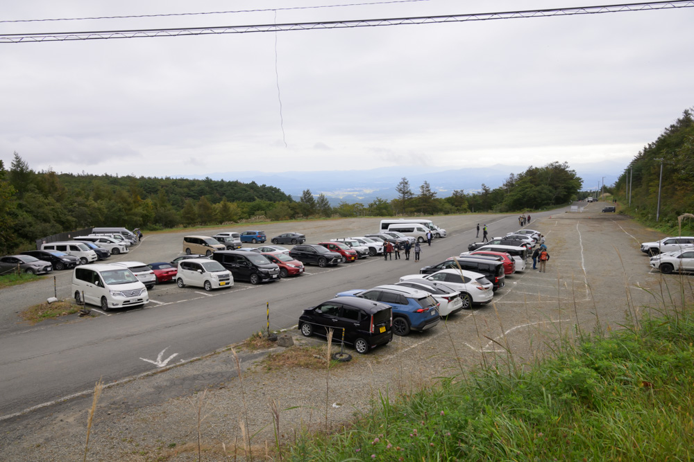 曇り空の下、車が並ぶあだたら山ロープウェイ近くの有料駐車場